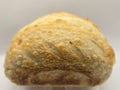 Loaf of bread in a clear plastic container on a white background